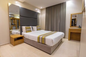 Ein modernes Hotelzimmer mit einem großen Bett, einem Nachttisch, einem Spiegel und einem Kleiderschrank.
