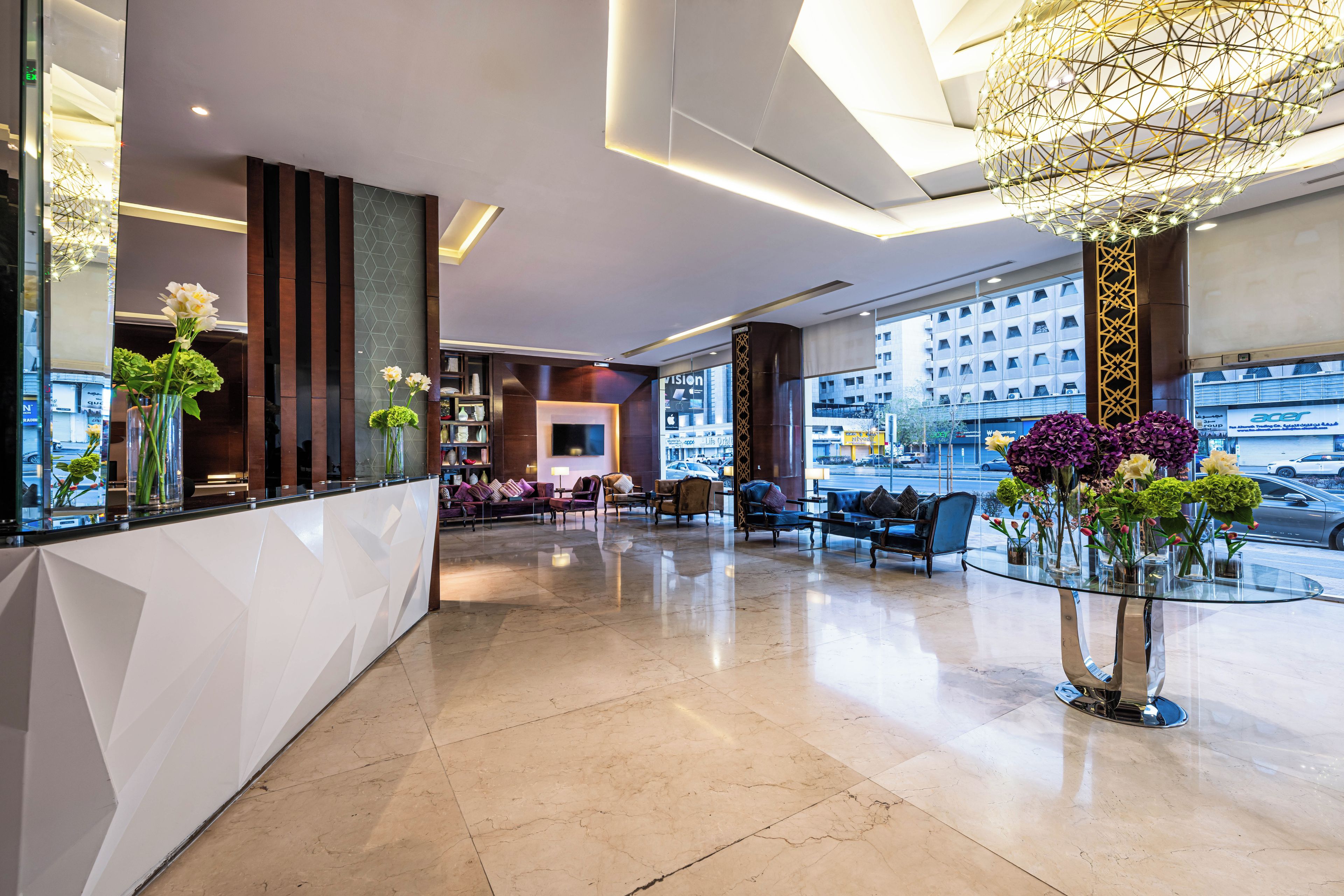 A modern lobby with a reception desk, seating area, and large windows.