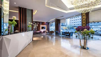 A modern lobby with a reception desk, seating area, and large windows.