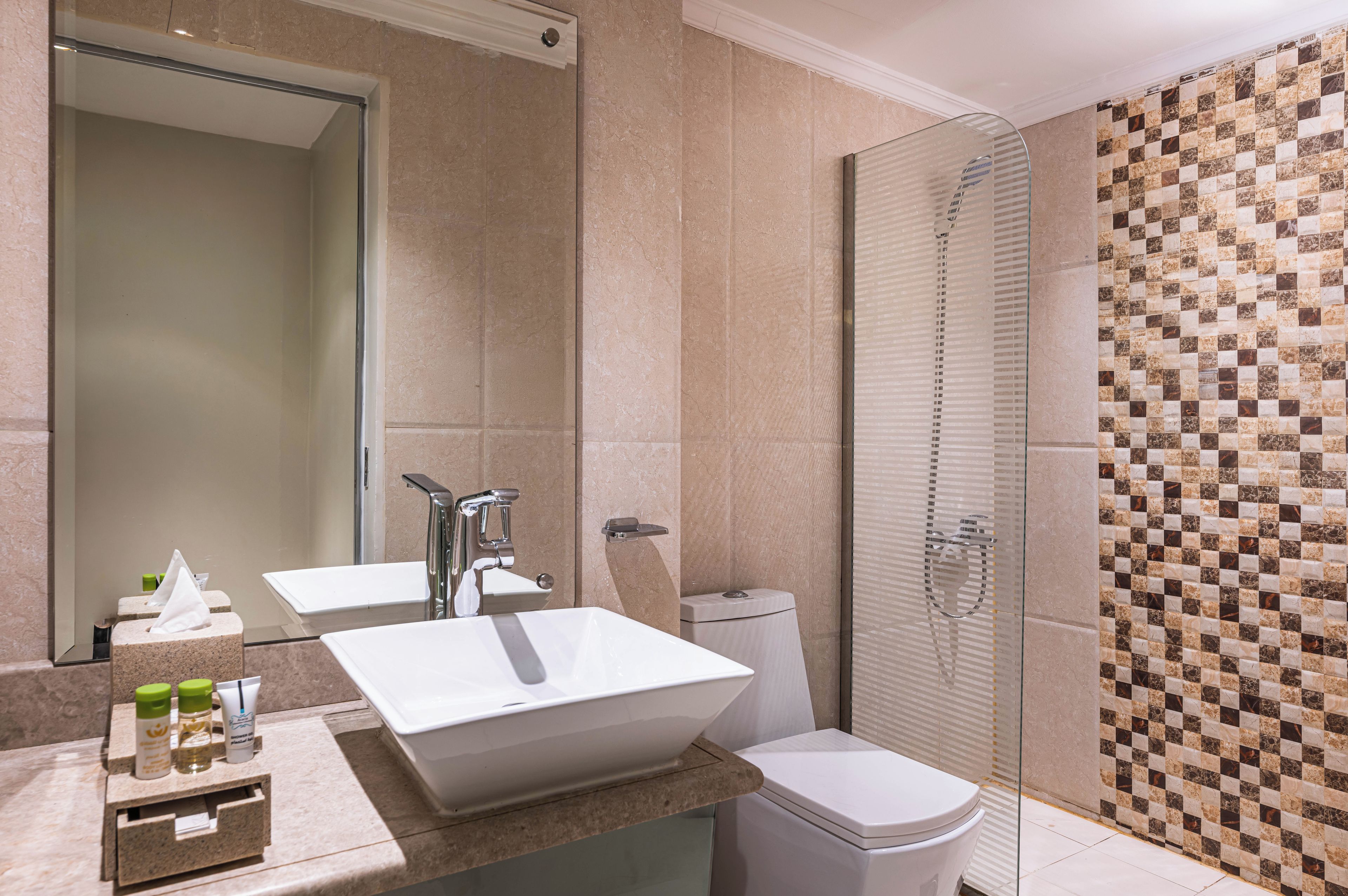 A modern bathroom with a large mirror, two sinks, a shower, and a toilet.
