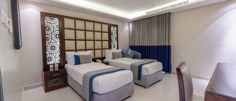 A hotel room with two beds, a desk, and a TV.