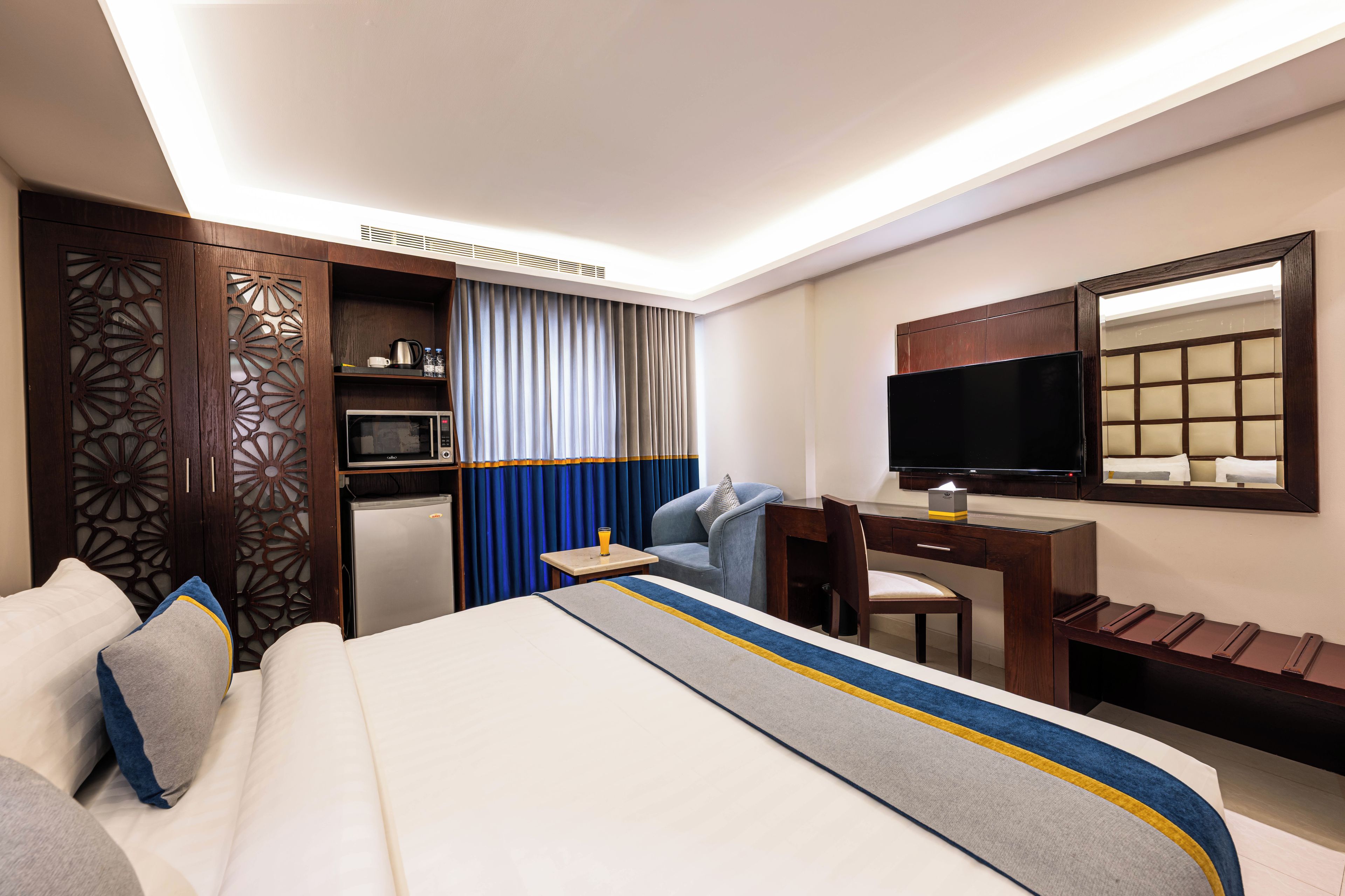 Una habitación de hotel con cama, escritorio, televisor y minibar.