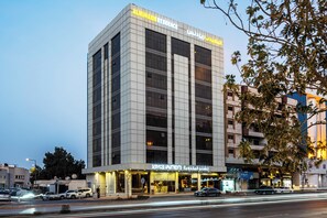 A multi-story hotel with a modern facade, large windows, and a sign indicating it offers serviced apartments.