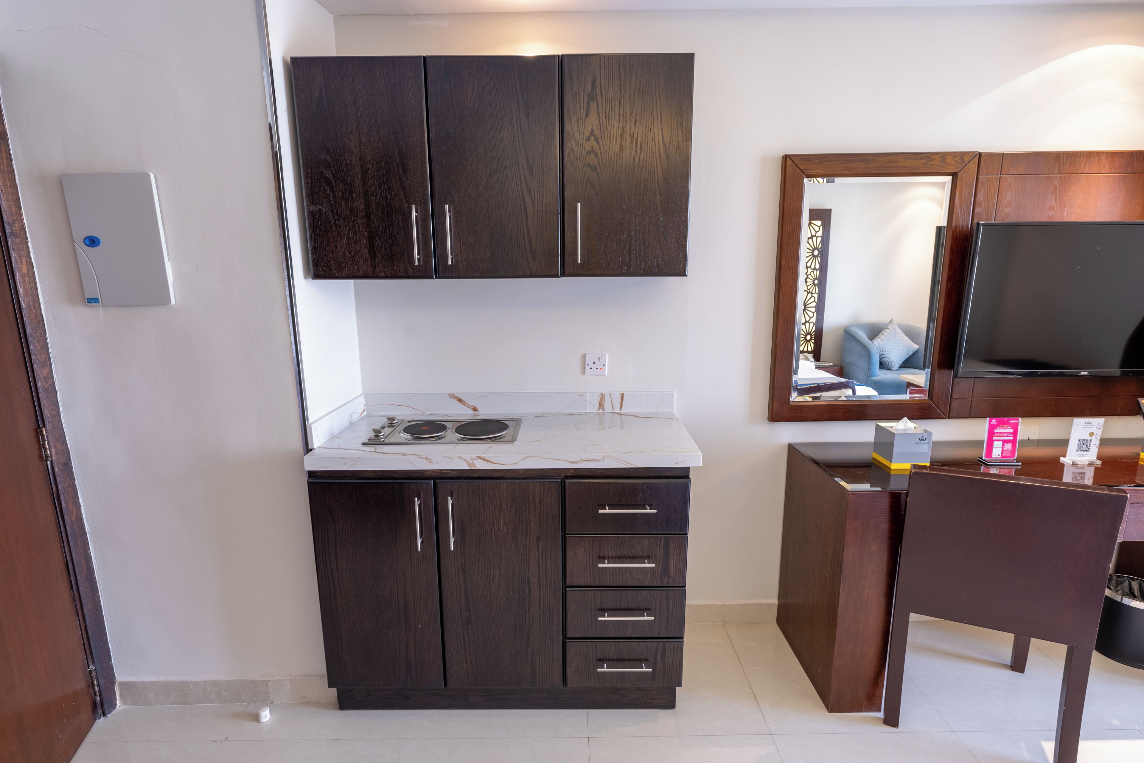 A modern kitchen with dark wood cabinets, a white countertop, and a built-in stove.