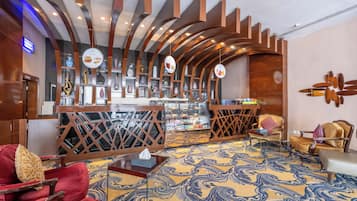 A hotel lobby with a bar area, seating arrangements, and a patterned carpet.