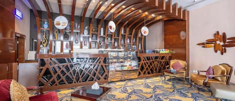 A hotel lobby with a bar area, seating arrangements, and a patterned carpet.