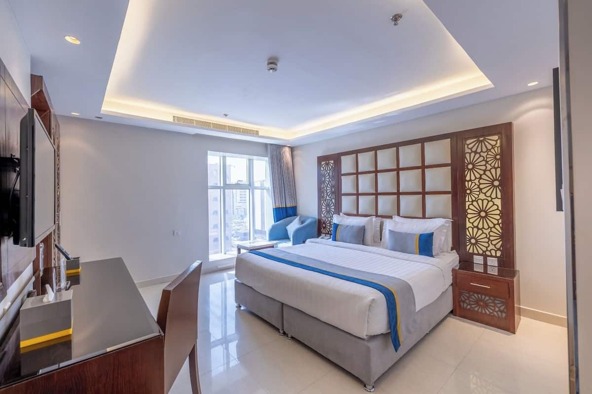A modern hotel room with a large bed, a desk, and a view of the city.