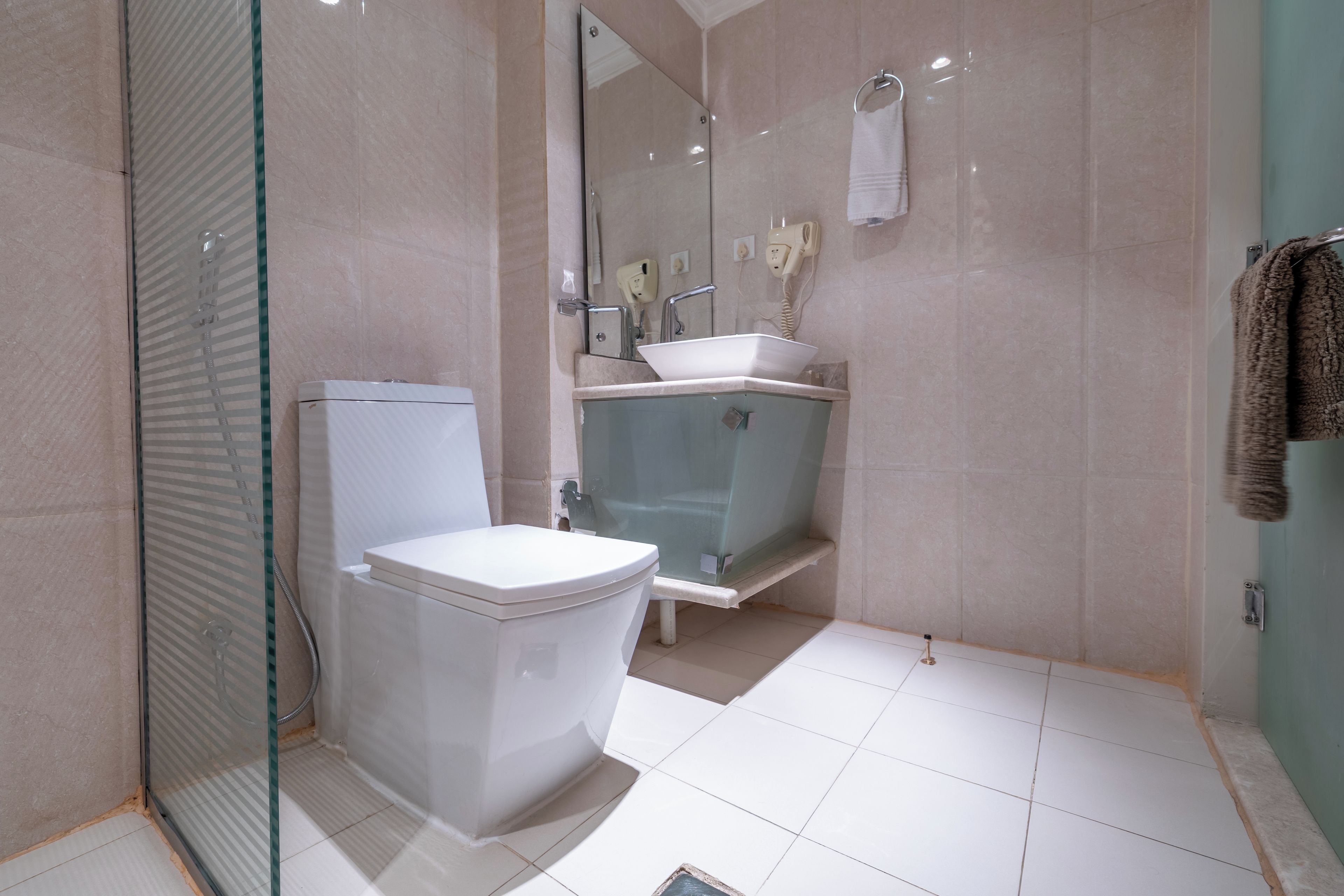 A modern bathroom with a toilet, a glass-enclosed shower, and a sink.
