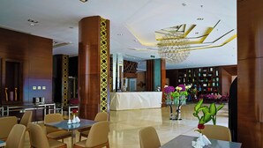 Een moderne hotel lobby met een receptiebalie, een zithoek en decoratieve planten.