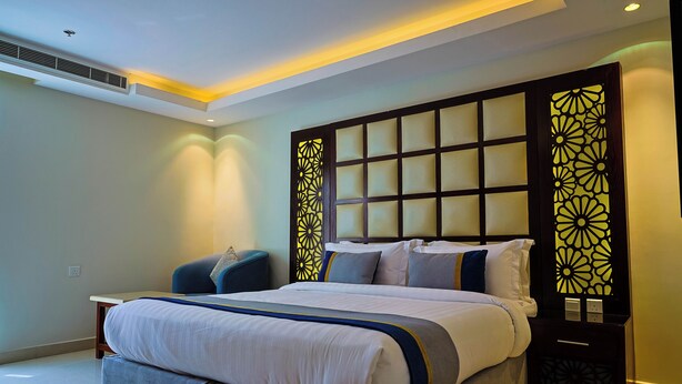 Een moderne hotelkamer met een groot bed, een nachtkastje en een decoratief wandpaneel.