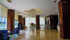 Een hotellobby met een moderne kroonluchter, een zithoek en een receptiebalie.