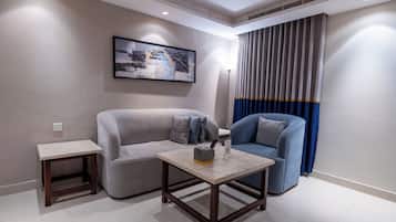 Un salon moderne avec un canapé gris, un fauteuil bleu, une petite table basse en bois et un lampadaire.