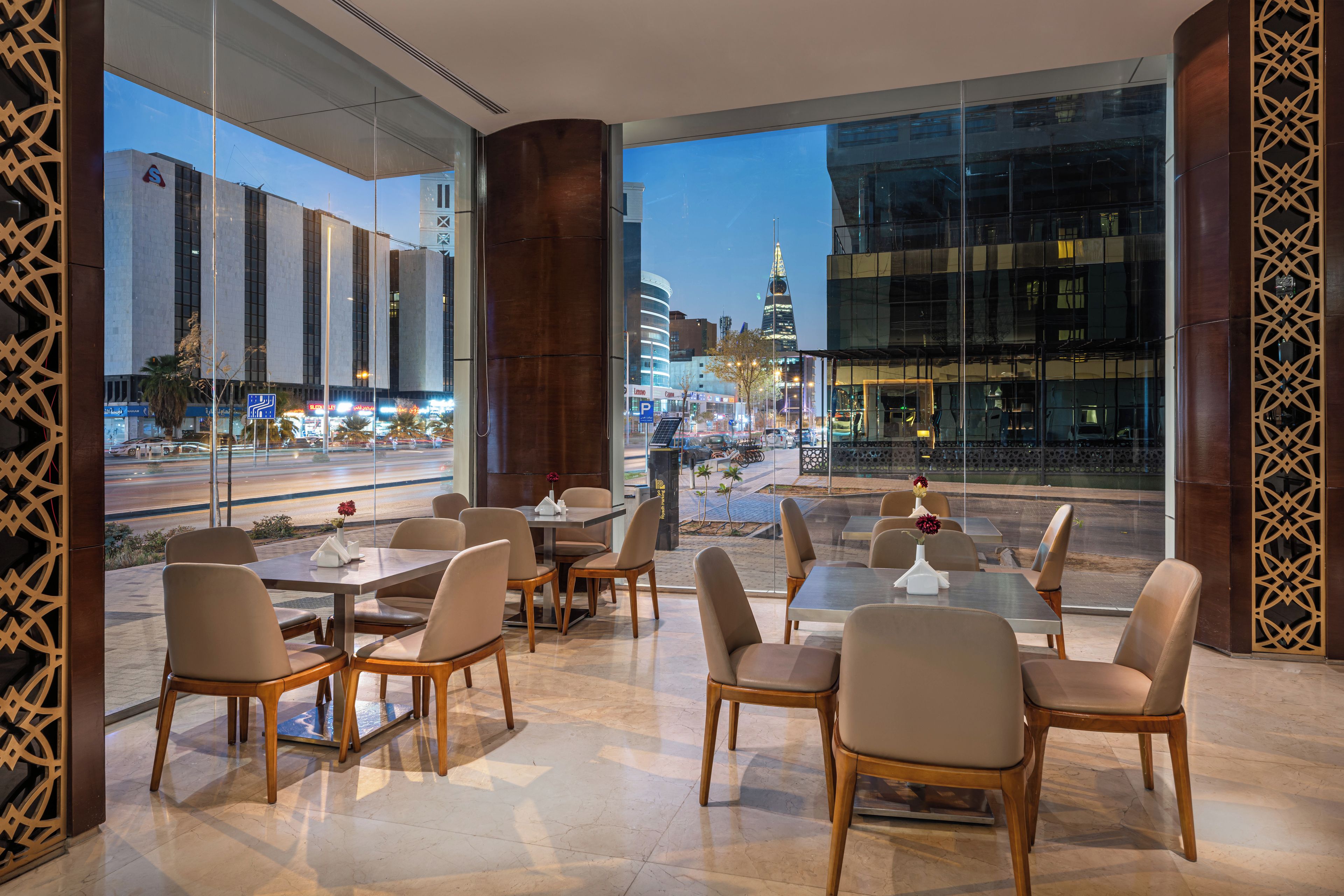 A modern restaurant with a view of a cityscape and a prominent building in the background.