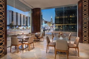 A modern restaurant with a view of a cityscape and a prominent building in the background. - AL Muhaidb ResidenceAl Olaya 1 - Economic (Riyadh)