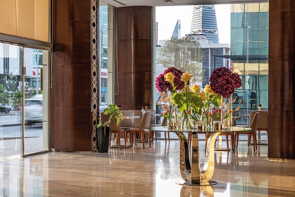 A modern interior with a glass table surrounded by chairs, a large window with a city view, and a decorative vase with flowers. - AL Muhaidb ResidenceAl Olaya 1 - Economic (Riyadh)
