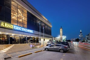 Un edificio moderno con un letrero que dice 'AL MUHAIDB RESIDENCE SERVICE APARTMENTS'.