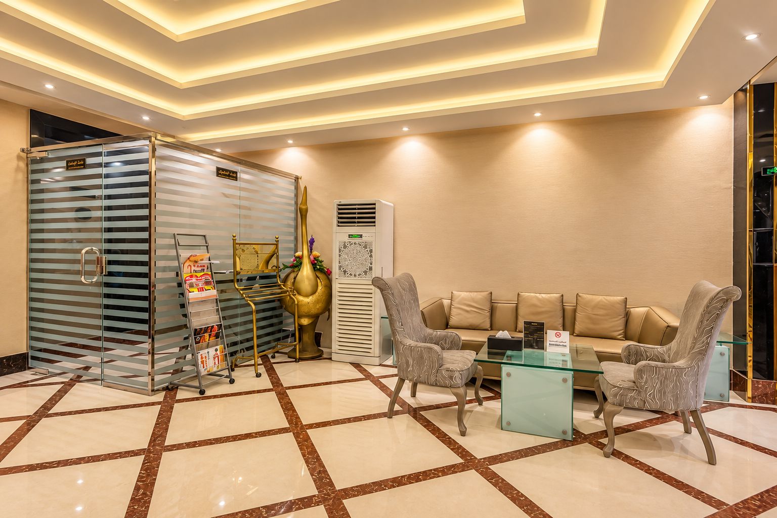Un vestíbulo de hotel con mostrador de recepción, zona de estar y un jarrón decorativo.