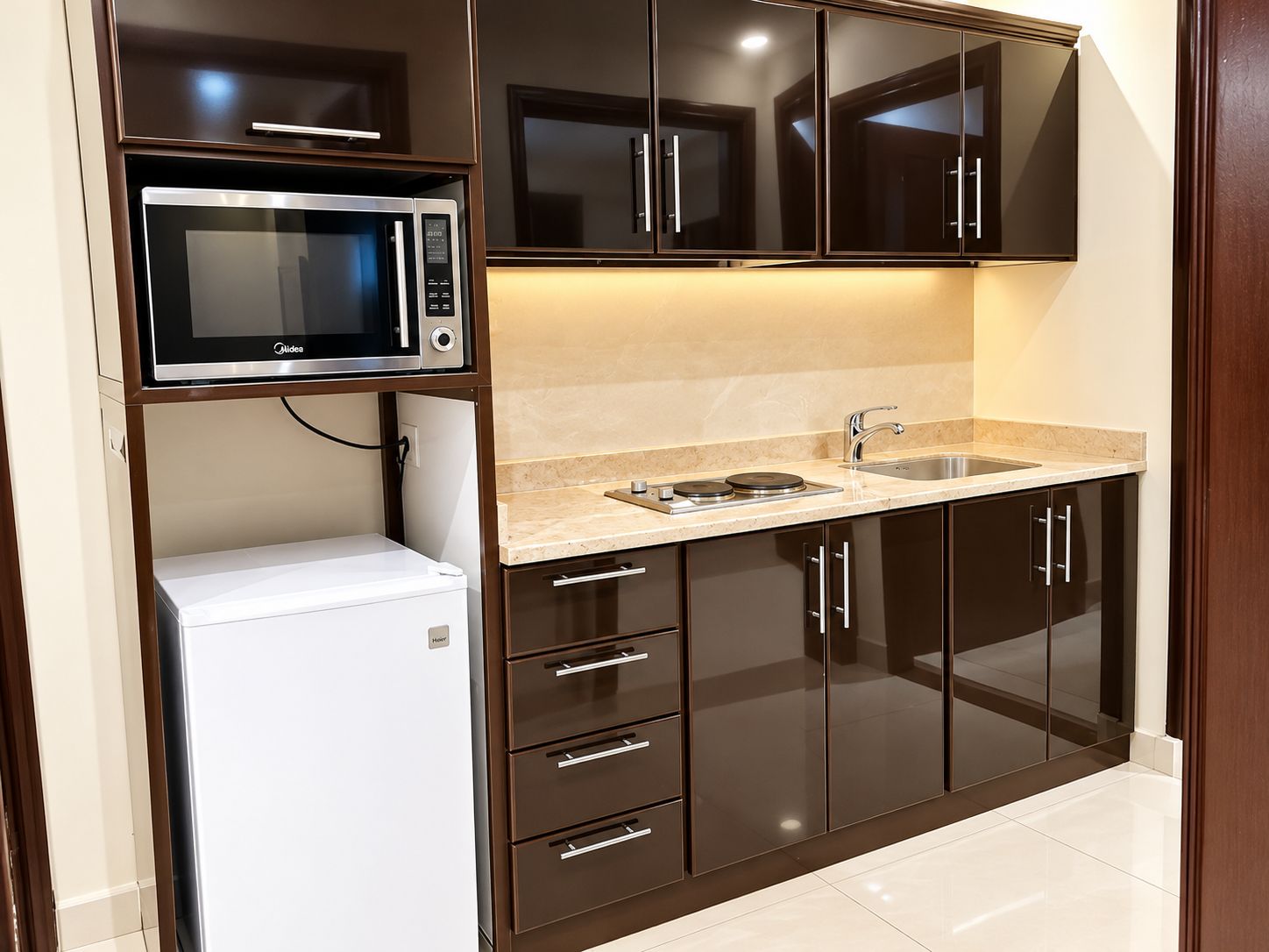 A compact kitchen with a built-in microwave, a small refrigerator, and a sink.