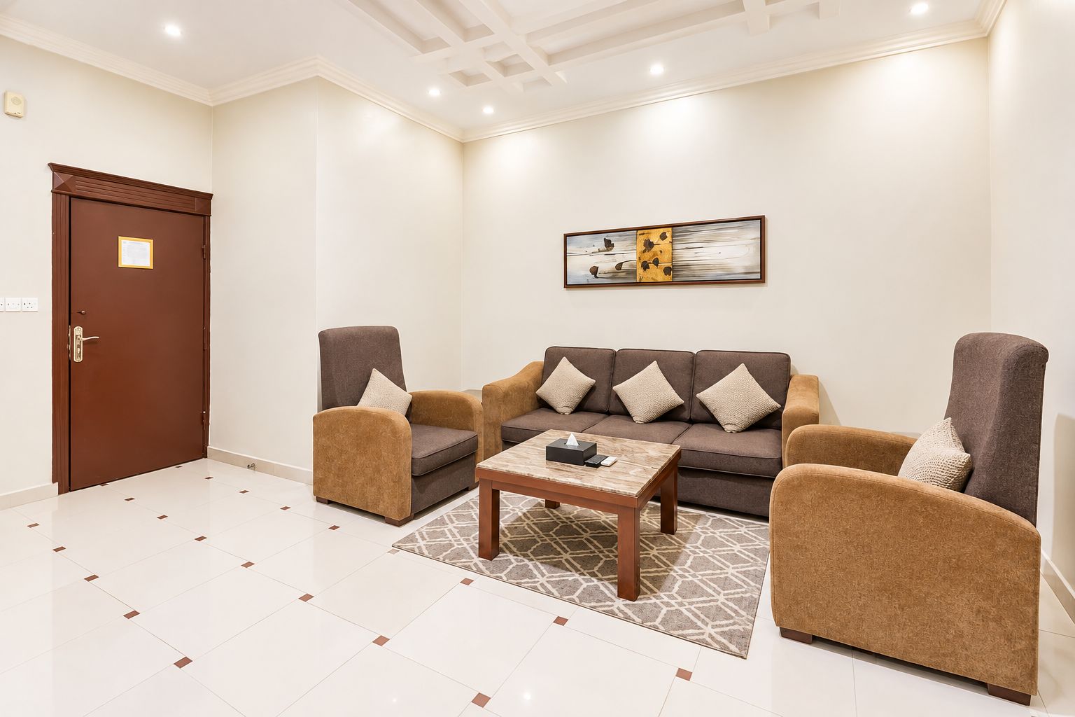 Una sala de estar moderna con un conjunto de sofás, sillones, una mesa de centro y un cuadro en la pared.