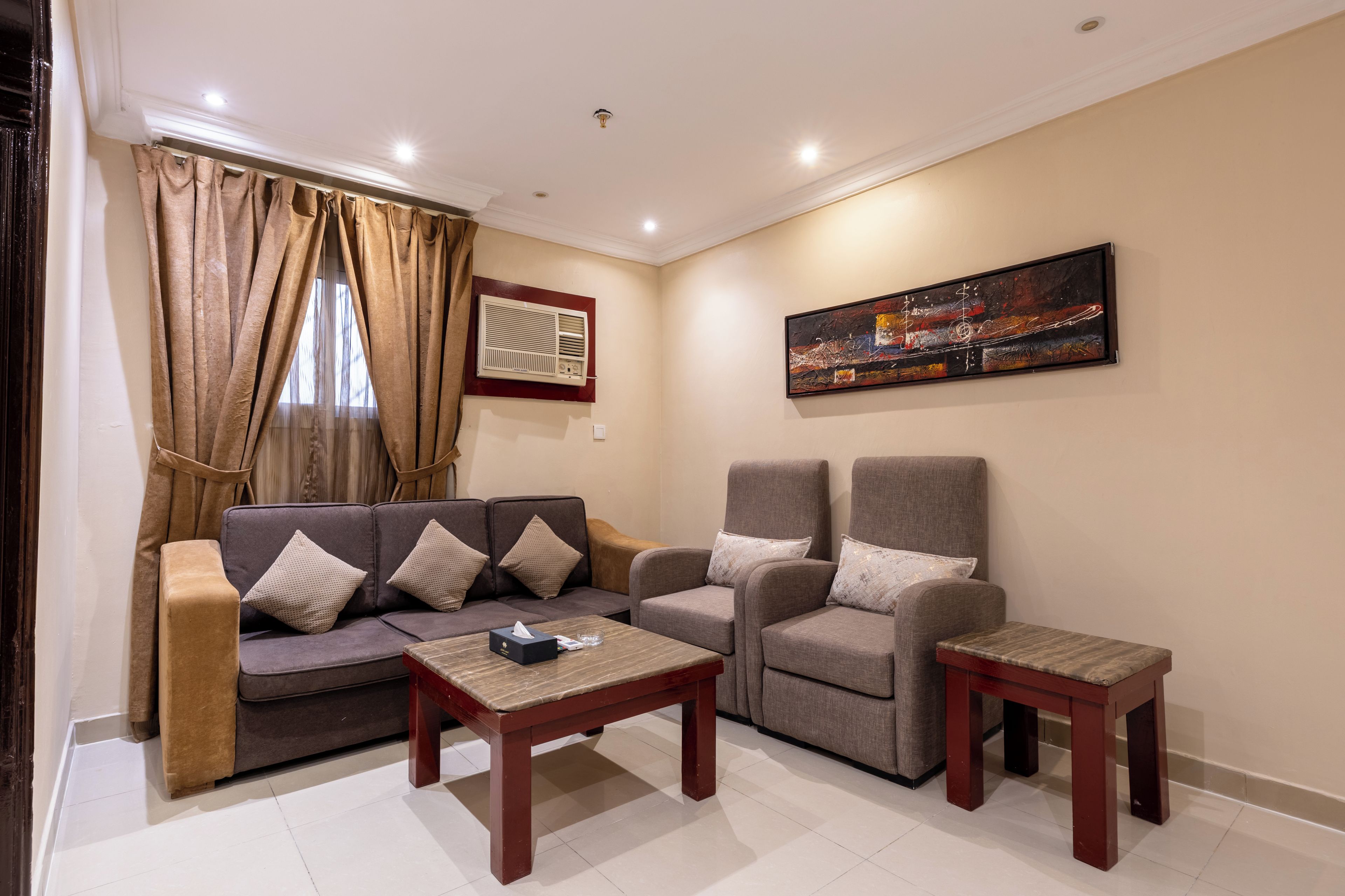 A living room with a sofa, two armchairs, a coffee table, and a painting on the wall.