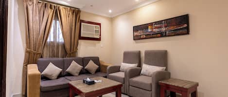 A living room with a sofa, two armchairs, a coffee table, and a painting on the wall.