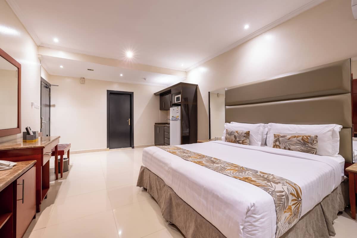 A modern bedroom with a large bed, a desk, and a wardrobe.