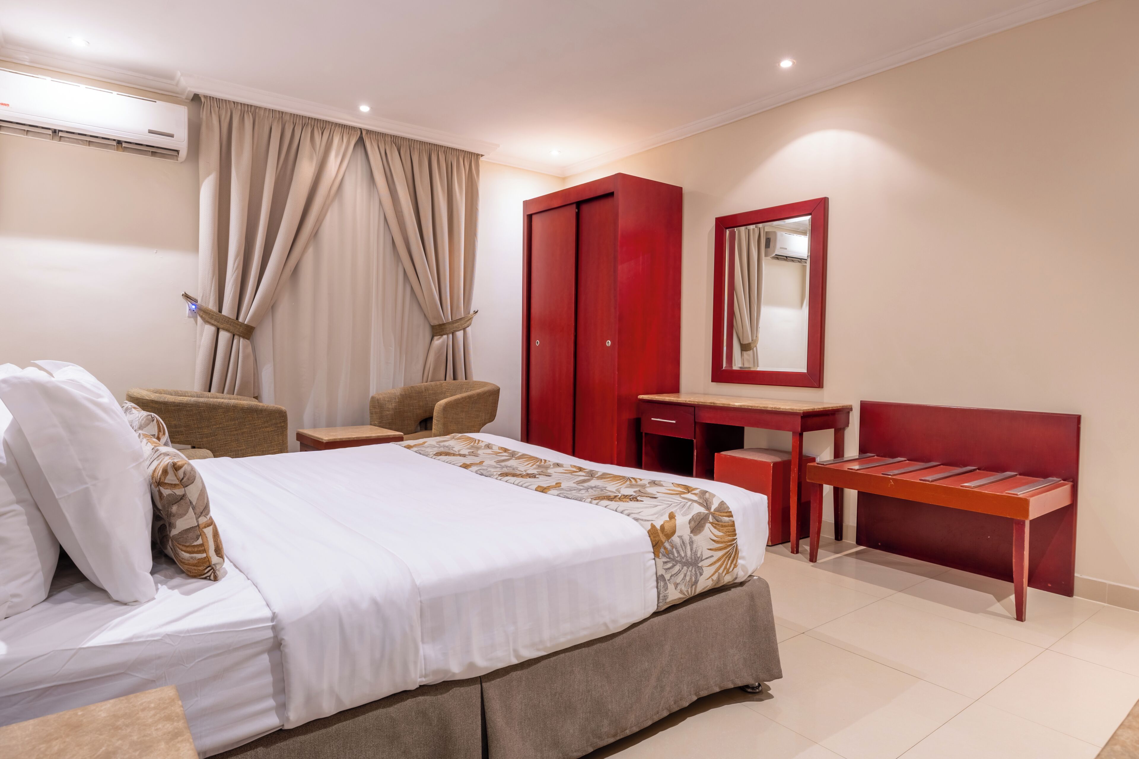 Une chambre d’hôtel comprenant un lit, un bureau, une chaise, une armoire et un miroir.