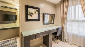 Une chambre moderne avec un grand lit, un bureau avec une chaise, un téléviseur à écran plat et une grande fenêtre avec des rideaux.