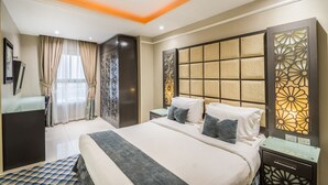 Une chambre d’hôtel moderne avec un grand lit, une table de chevet, une armoire et un élément de séparation décoratif.
