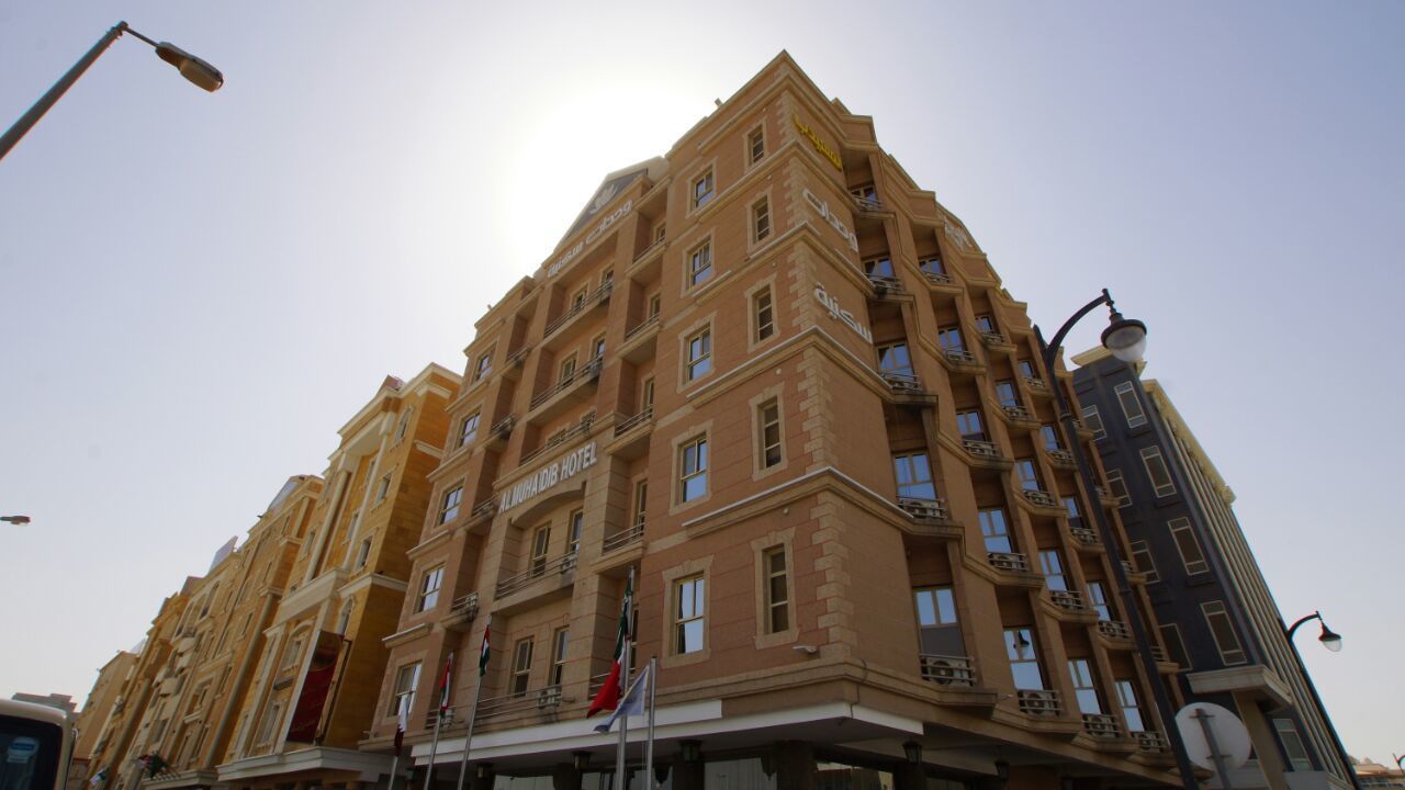 Un hôtel à plusieurs étages doté de balcons, d’une enseigne indiquant qu’il s’agit d’un hôtel et de drapeaux.
