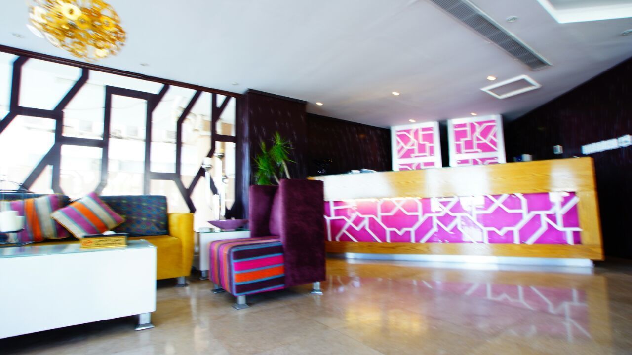 Un hall d’entrée moderne avec un comptoir d’accueil, un espace salon et une grande fenêtre.