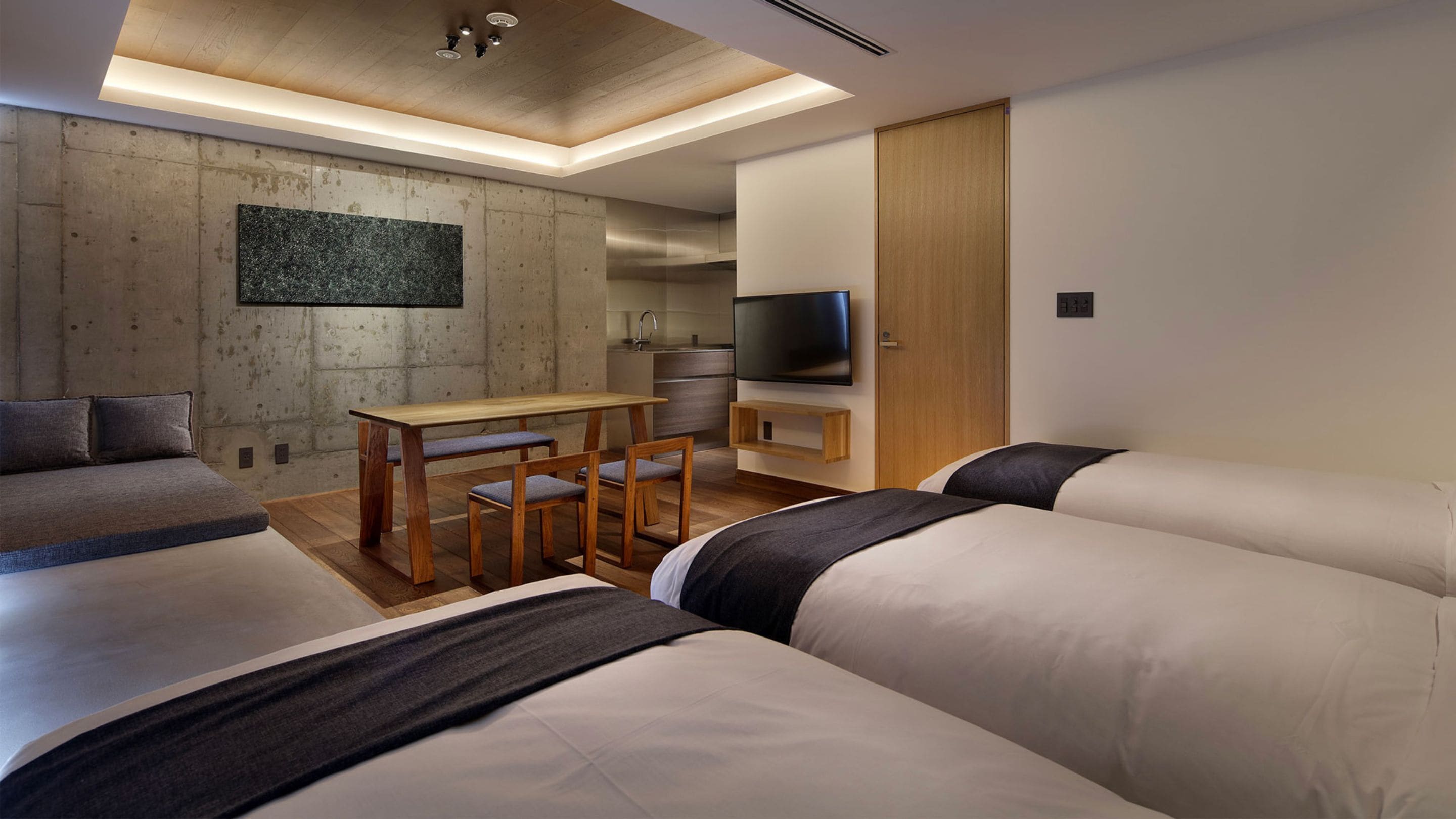 A modern hotel room with a dining area, a TV, and a large artwork on the wall.