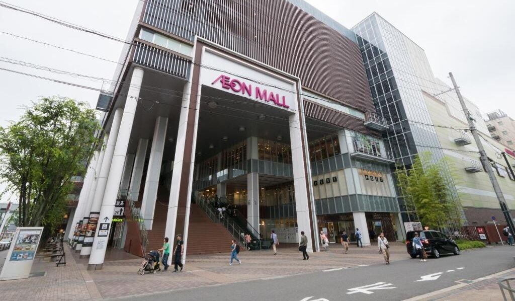 Ein modernes AEON MALL Gebäude mit einem markanten Eingang und mehreren Stockwerken.