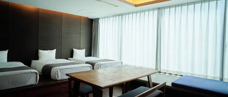 A hotel room with a large bed, a smaller bed, a desk, and a bench.