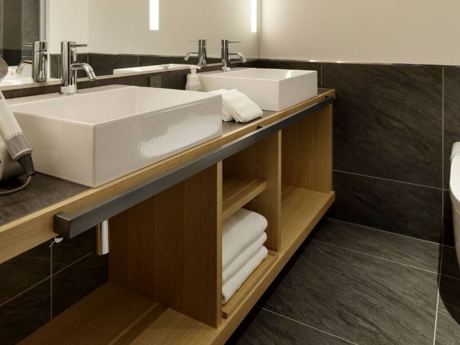 A modern bathroom with two sinks, a hairdryer, and a toilet.