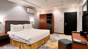 Een hotelkamer met een bed, een bureau, een televisie, een kledingkast en een airconditioning.