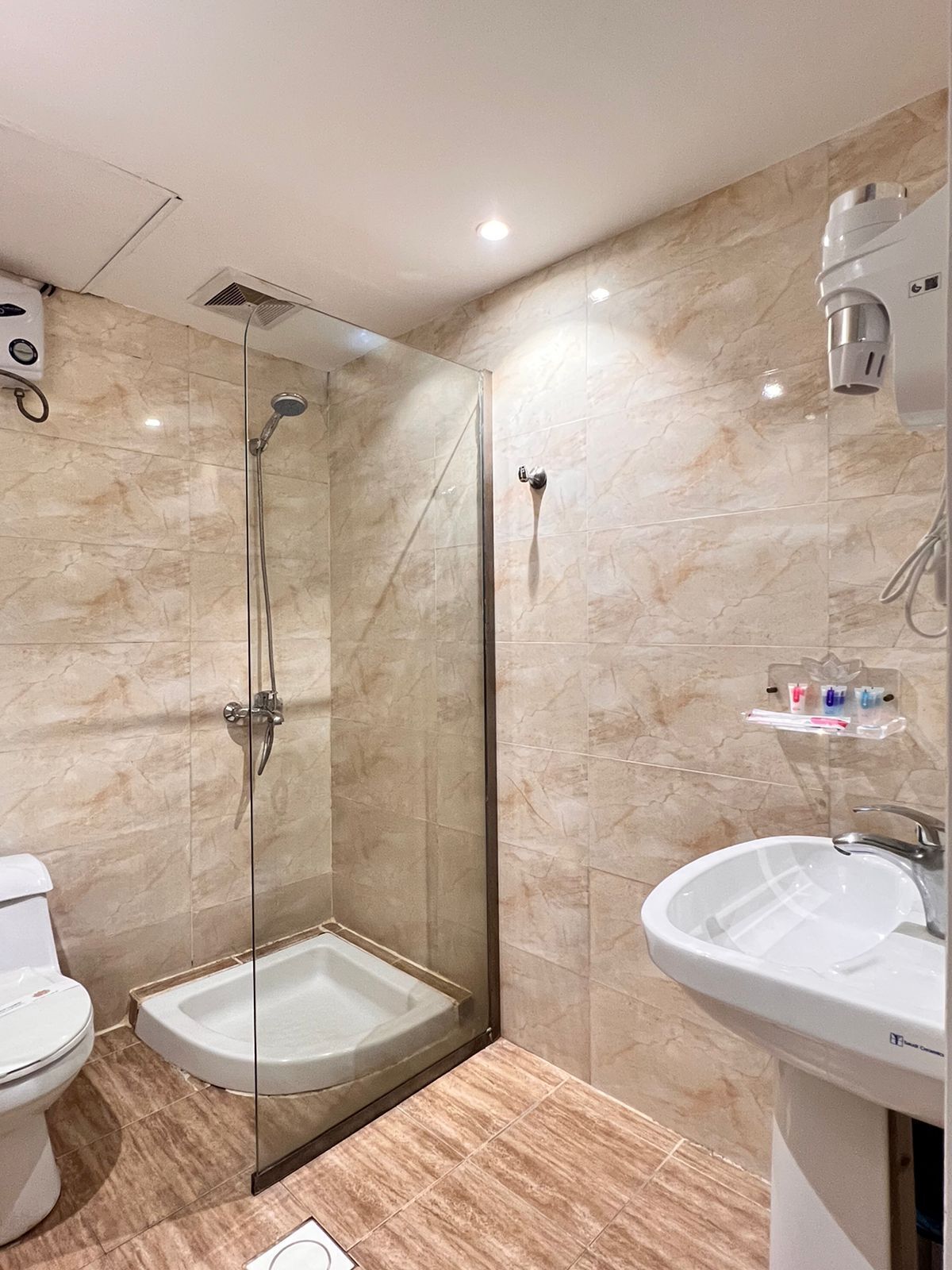 A modern bathroom with a glass-enclosed shower, a white sink, and a toilet.