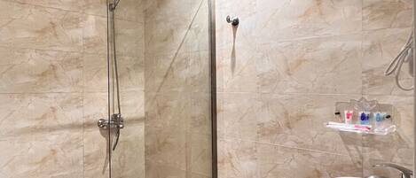 A modern bathroom with a glass-enclosed shower, a white sink, and a toilet.