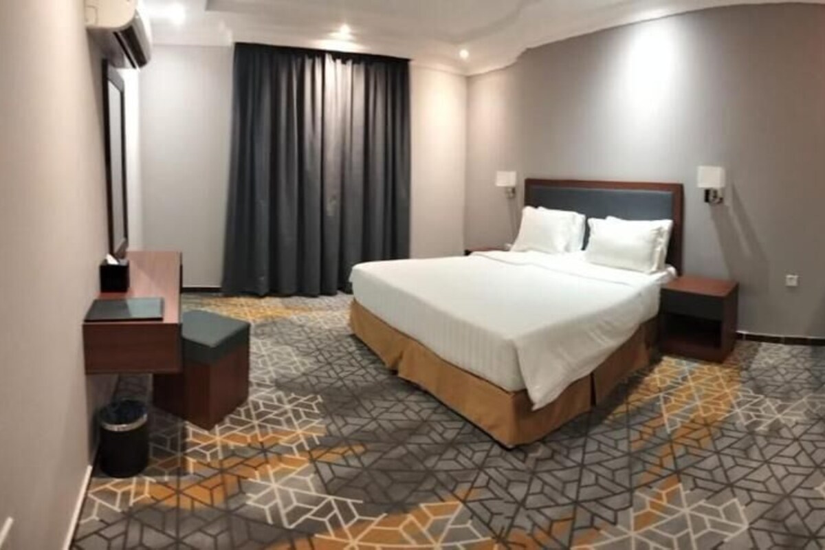 Une chambre d’hôtel avec un grand lit, des tables de chevet, une armoire et un sol à motifs.