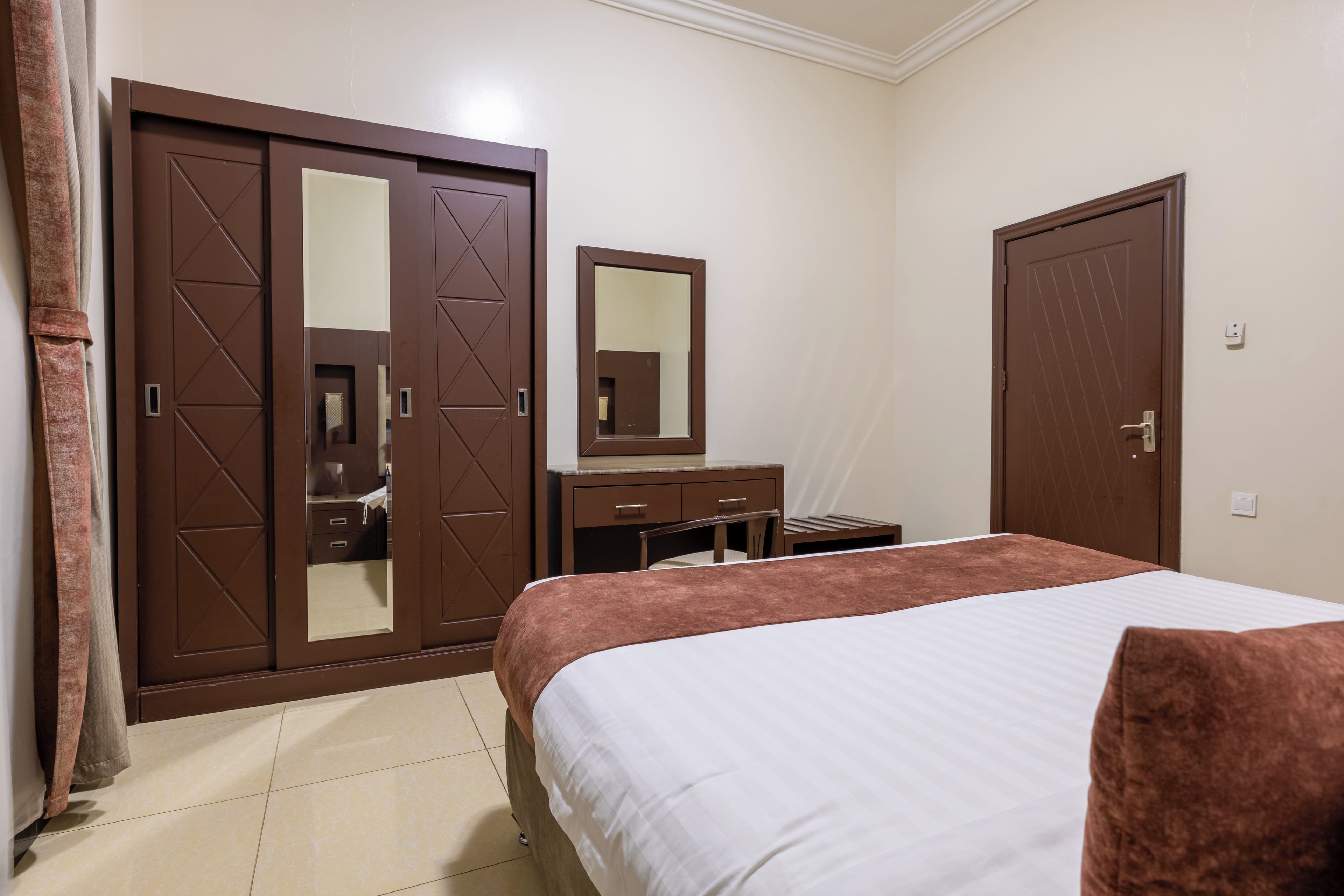 Un dormitorio con cama, cómoda, espejo y dos armarios.