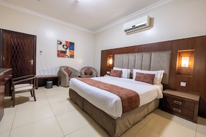 A hotel room with a large bed, bedside tables, a desk, a chair, and an air conditioning unit. - Al Muhaidb Residence Al Malaz  6 - Economic (Riyadh)