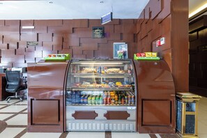 Máquina de vendas automática com lanches e bebidas, placa de cafeteria e placa de centro de negócios em um interior moderno.