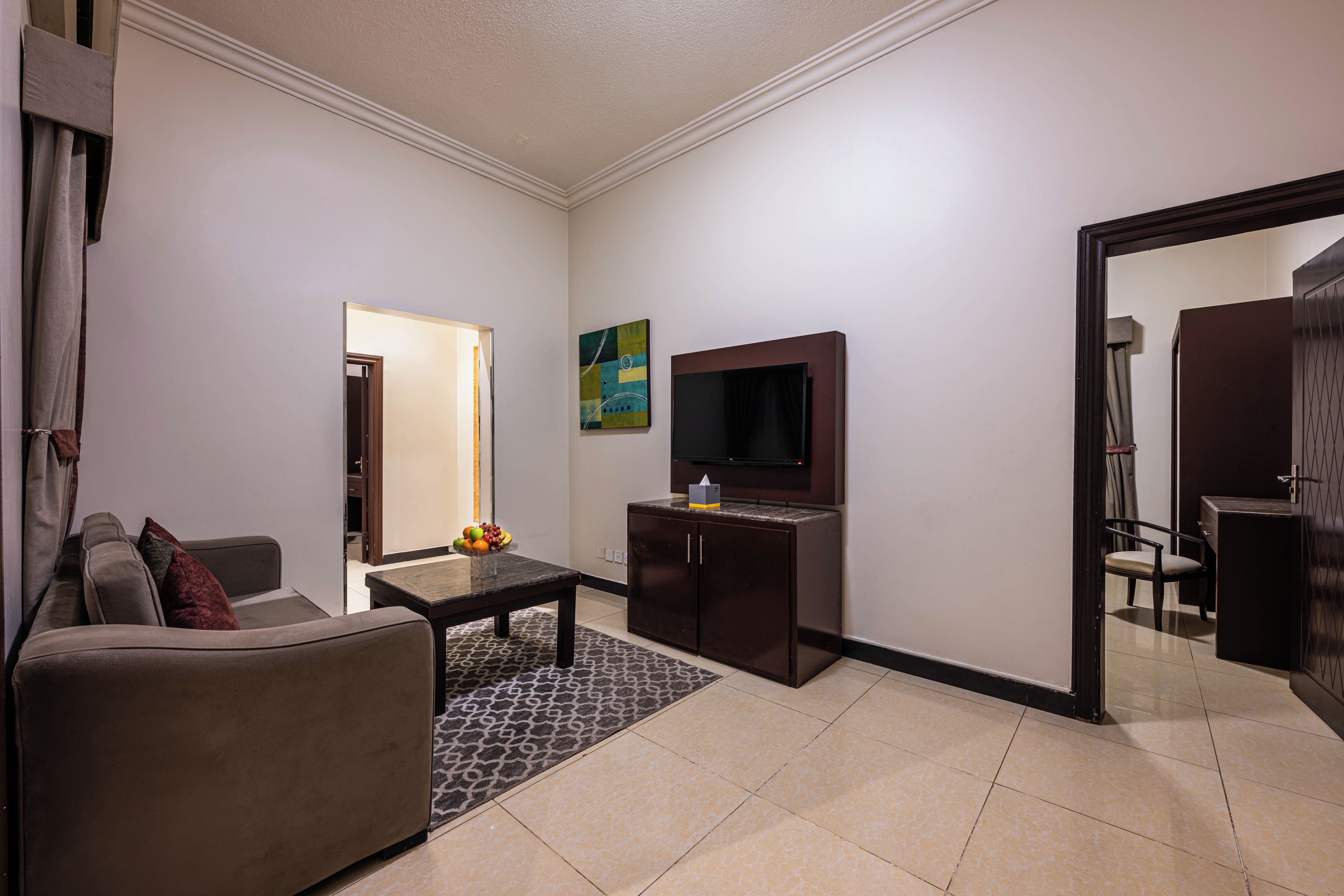 A modern living room with a sofa, a coffee table, a flat-screen TV, and a cabinet.