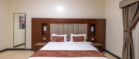 A hotel room with a large bed, a nightstand, a mirror, and a window with curtains.
