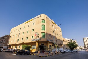 Un hotel de diverses plantes amb un senyal ben visible que diu 'Al Muhajid Residence' i 'Apartaments amb servei'.
