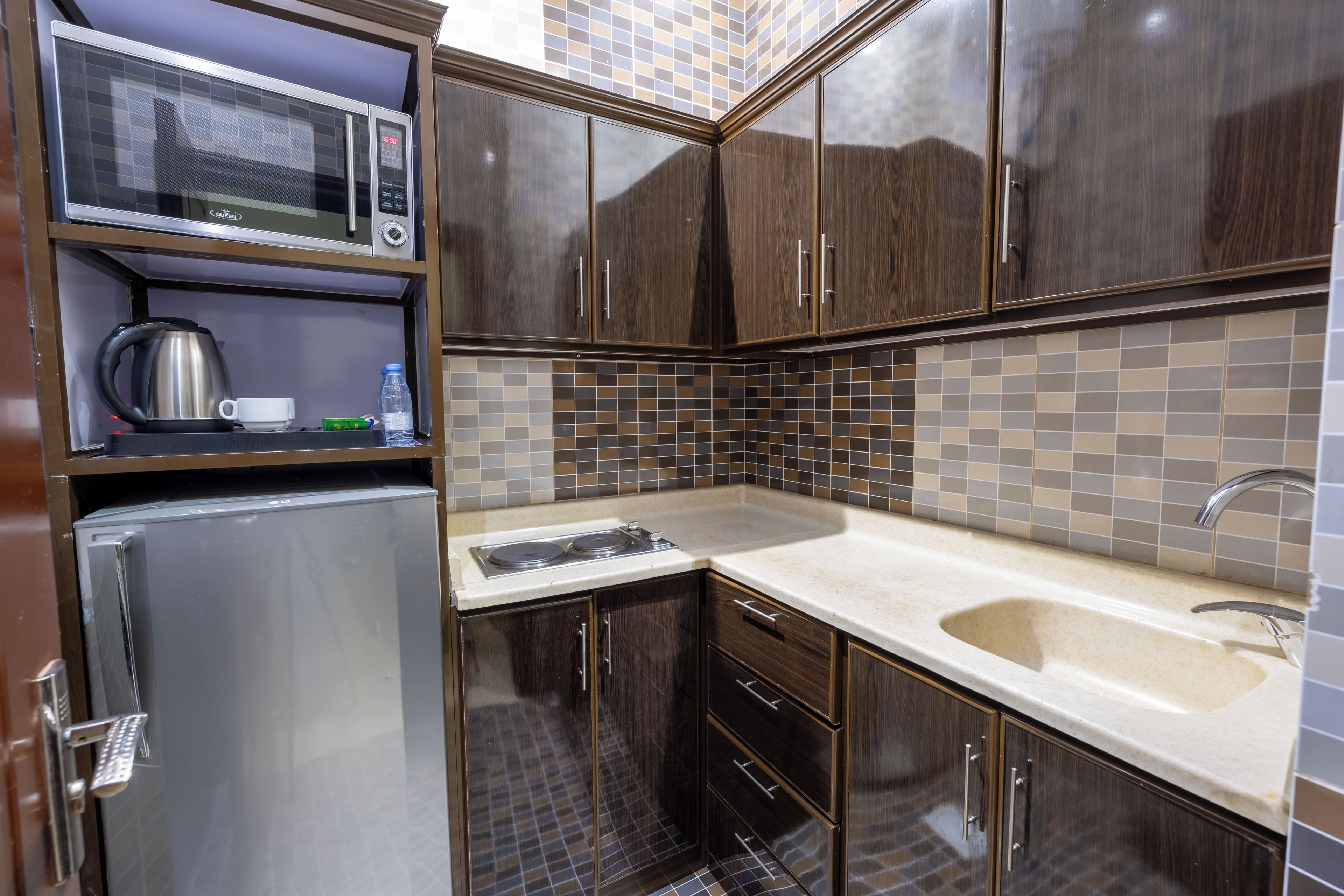 Cocina compacta con microondas, hervidor y refrigerador integrados.