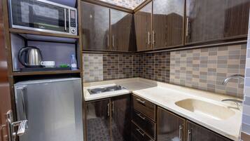 Cocina compacta con microondas, hervidor y refrigerador integrados.
