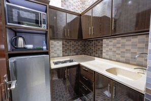 A compact kitchen with a built-in microwave, kettle, and refrigerator. - Al Muhaidb Residence Al Malaz  6 - Economic (Riyadh)
