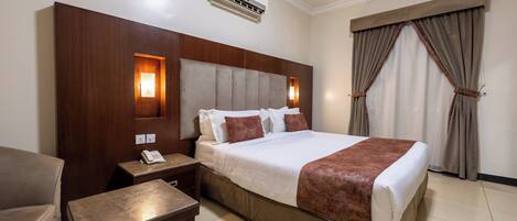 Quarto de hotel com cama, mesa de cabeceira e telefone.