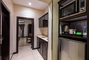 A compact kitchen with a microwave, kettle, and water bottle on the counter. - Al Muhaidb Residence Al Malaz  6 - Economic (Riyadh)